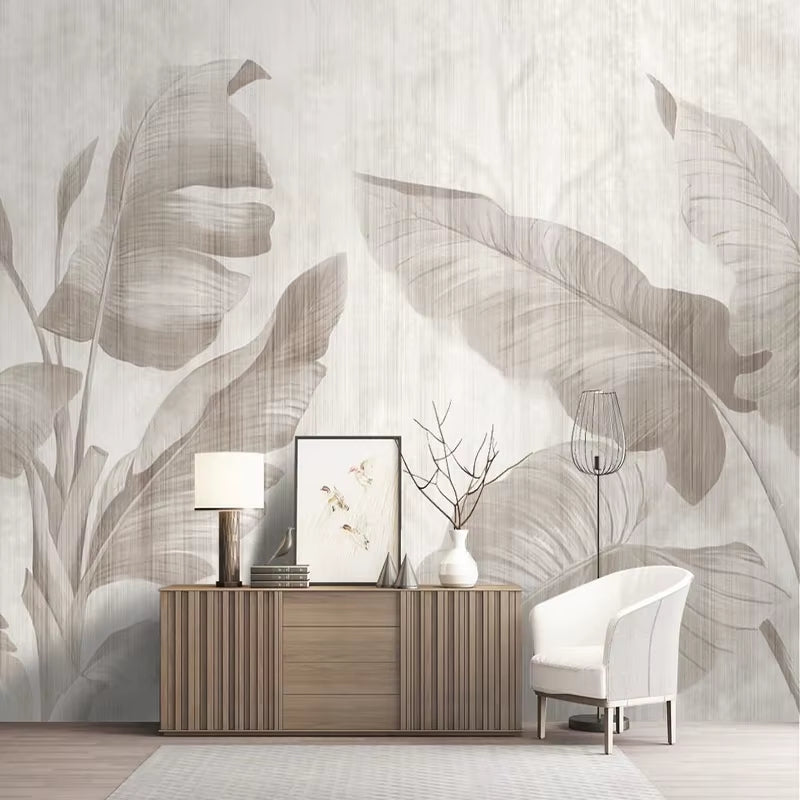 Papier peint panoramique Feuilles de bananier posé derrière un buffet en bois cannelé, fauteuil blanc et lampe à poser