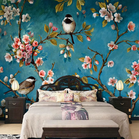 Papier peint panoramique Les Mésanges derrière un lit en bois sombre, linge beige et rose et chevets assortis