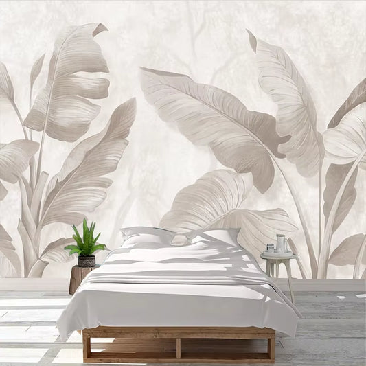 Papier peint panoramique Feuilles de bananier derrière un lit bas en bois, linge blanc et plante verte